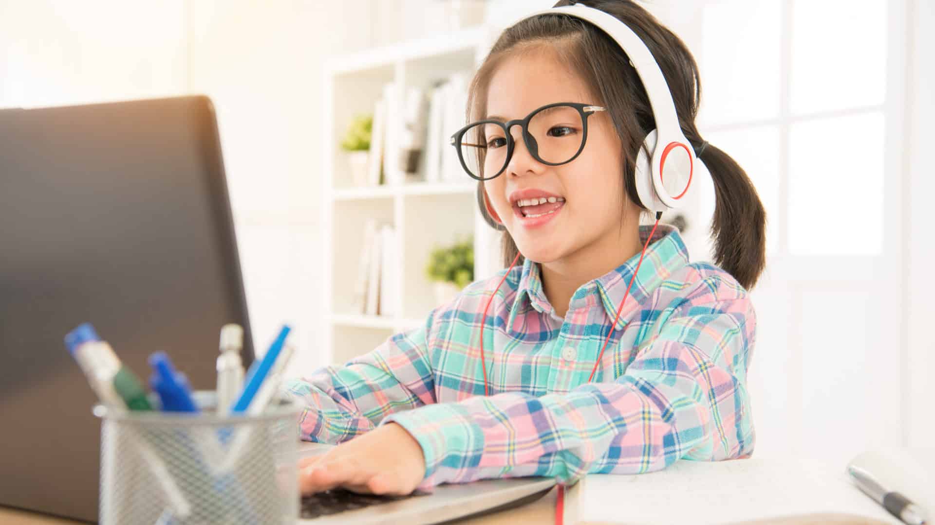 Çocuklar için online İngilizce eğitimi alan kulaklıklı ve gözlüklü kız çocuğu kapak görseli